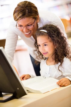 Girl at school with her teacher learning to use technology