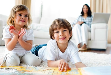 Jolly siblings eating chips and drawing lying on the floor