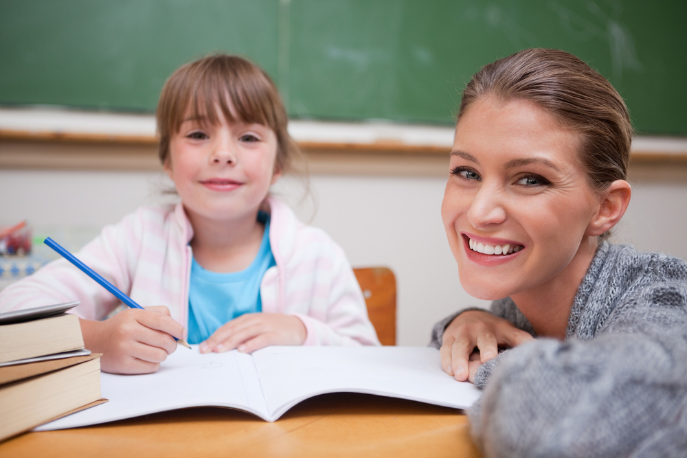 a happy tutor and her young student working on book work