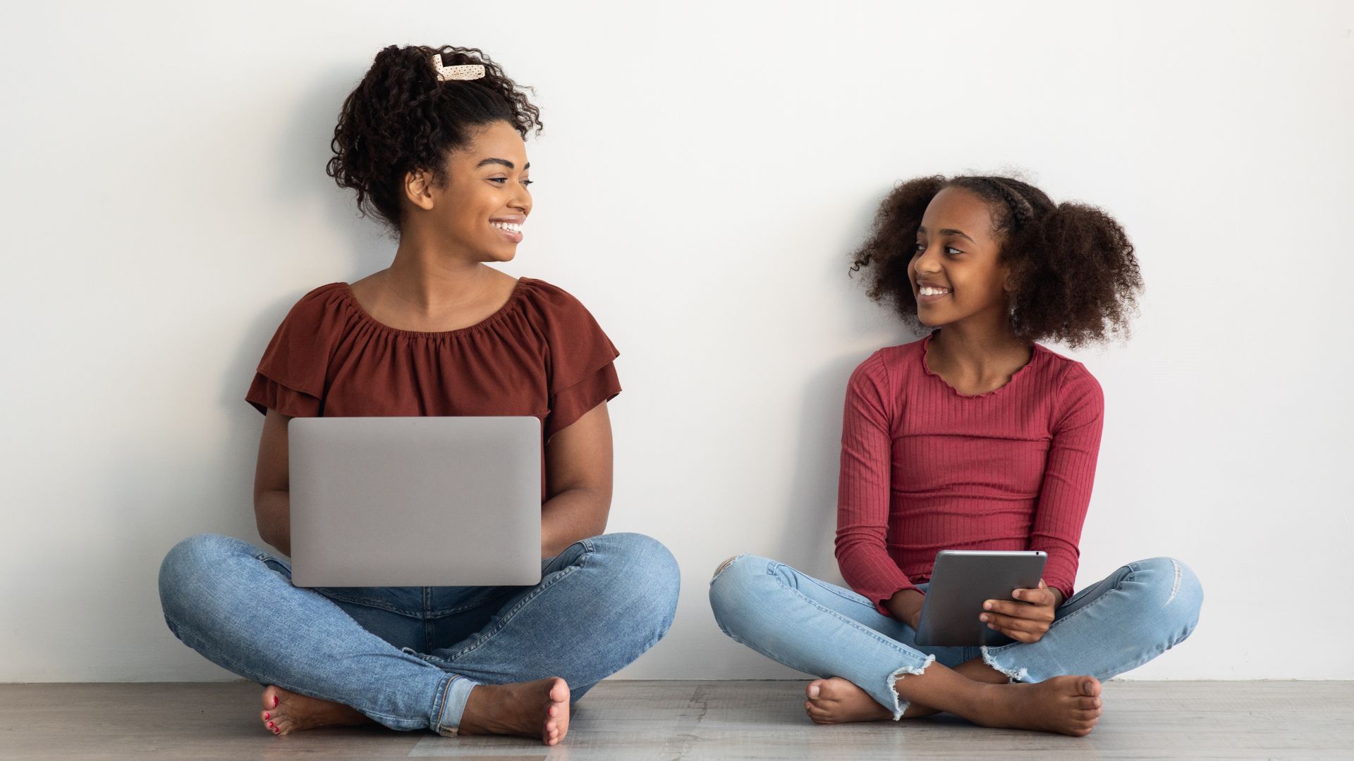 Mom and daughter working on laptop and tablet, smiling